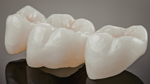 3 dental crowns with a grey background