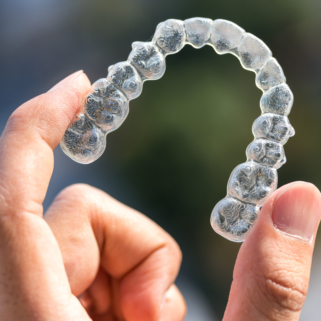 hand holding clear aligners in the sky