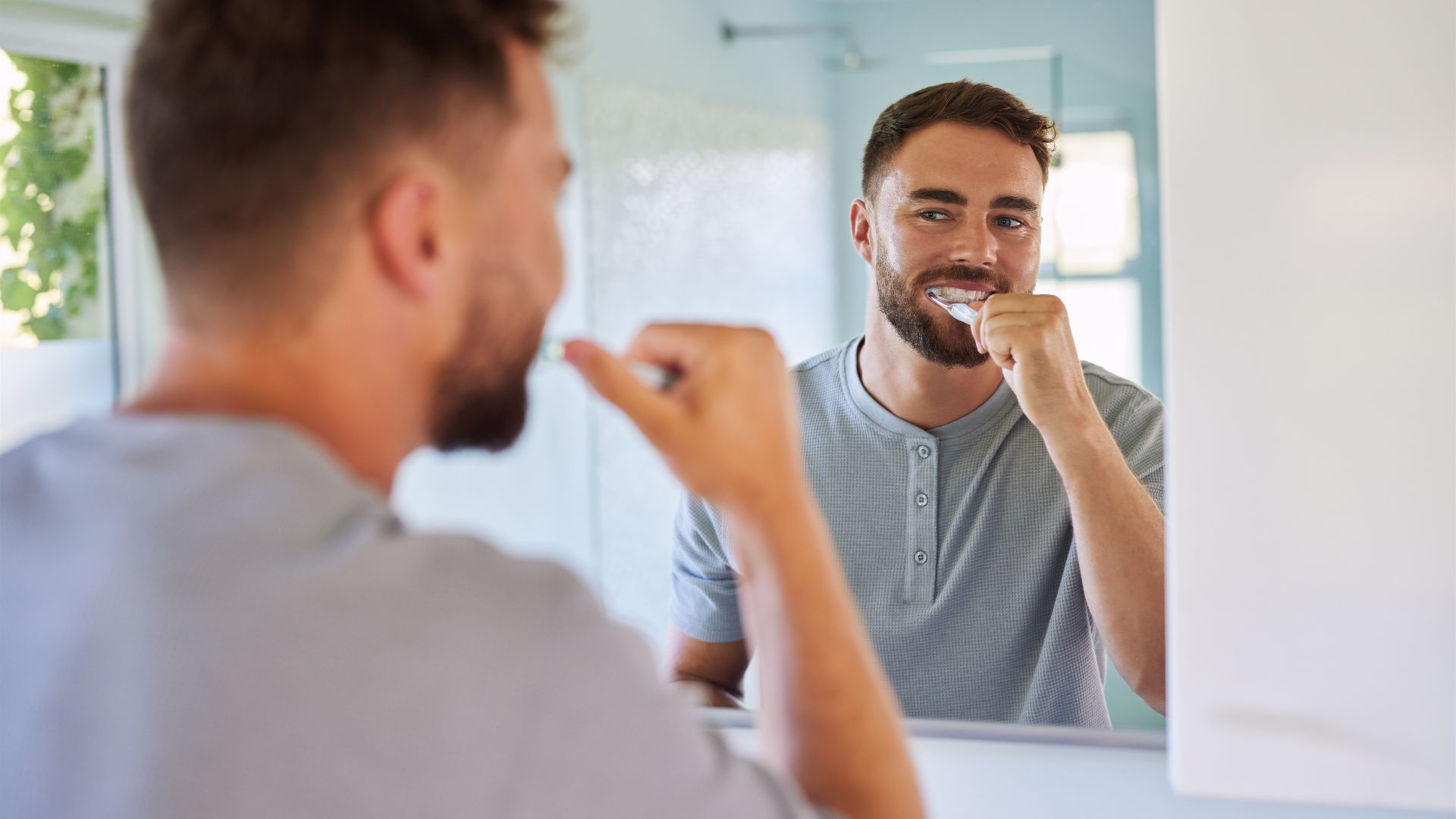 man brushing teeth in the mirror 